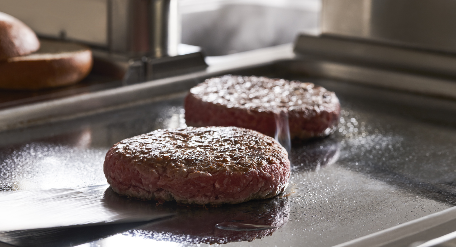 Hamburger che cuociono su una piastra rovente in una cucina Tecnoinox